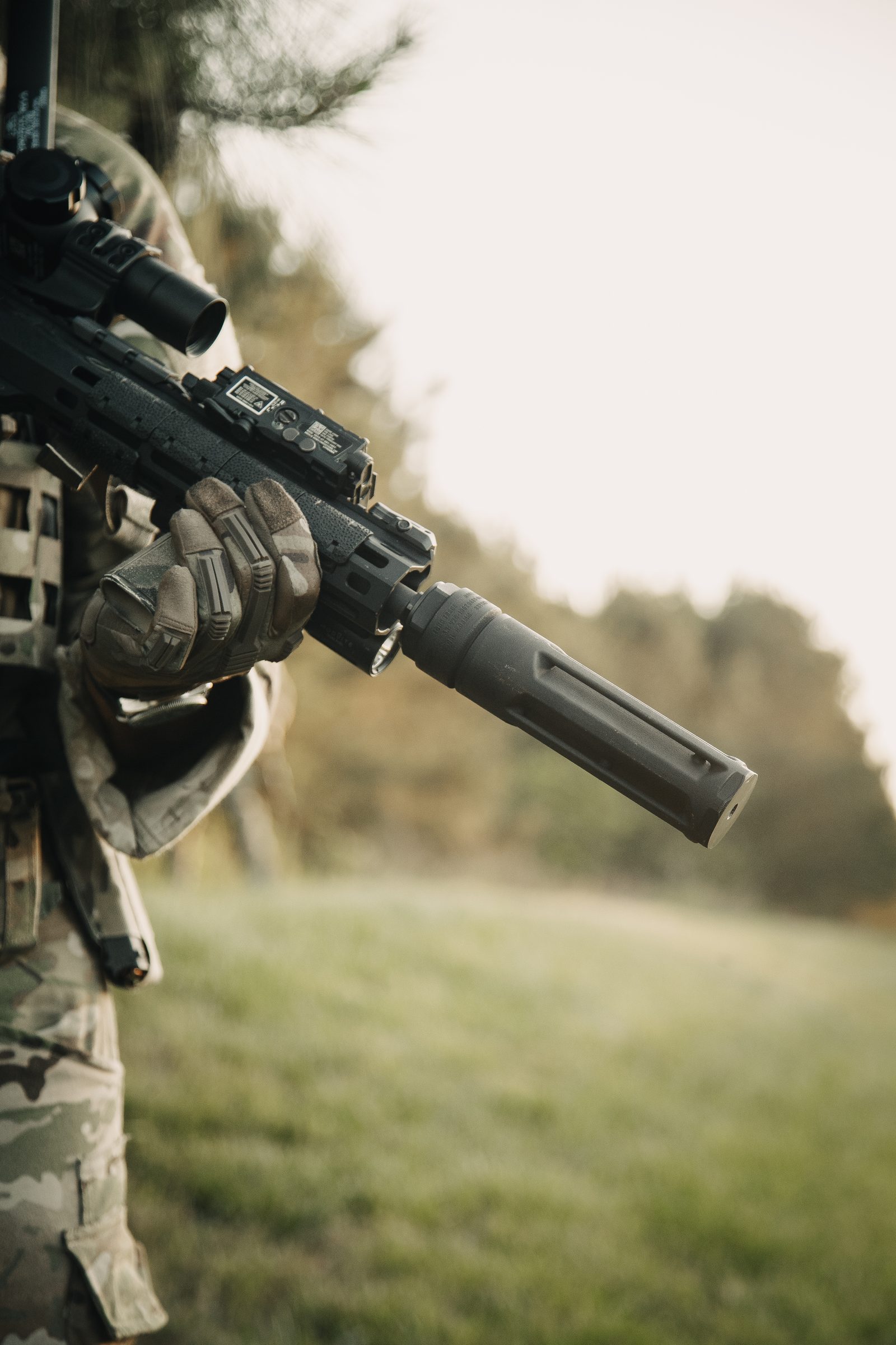 Operator with suppressed rifle in a field environment